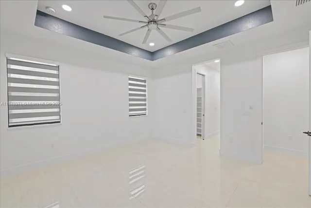 en empty room with windows and ceiling fan