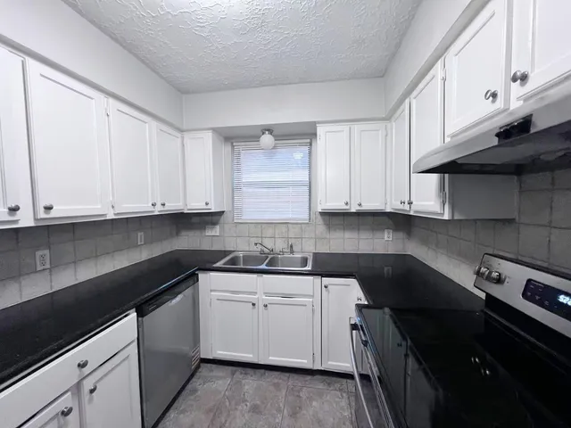 a kitchen with a sink dishwasher and white cabinets