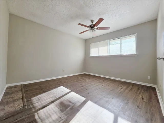 an empty room with a window and ceiling fan