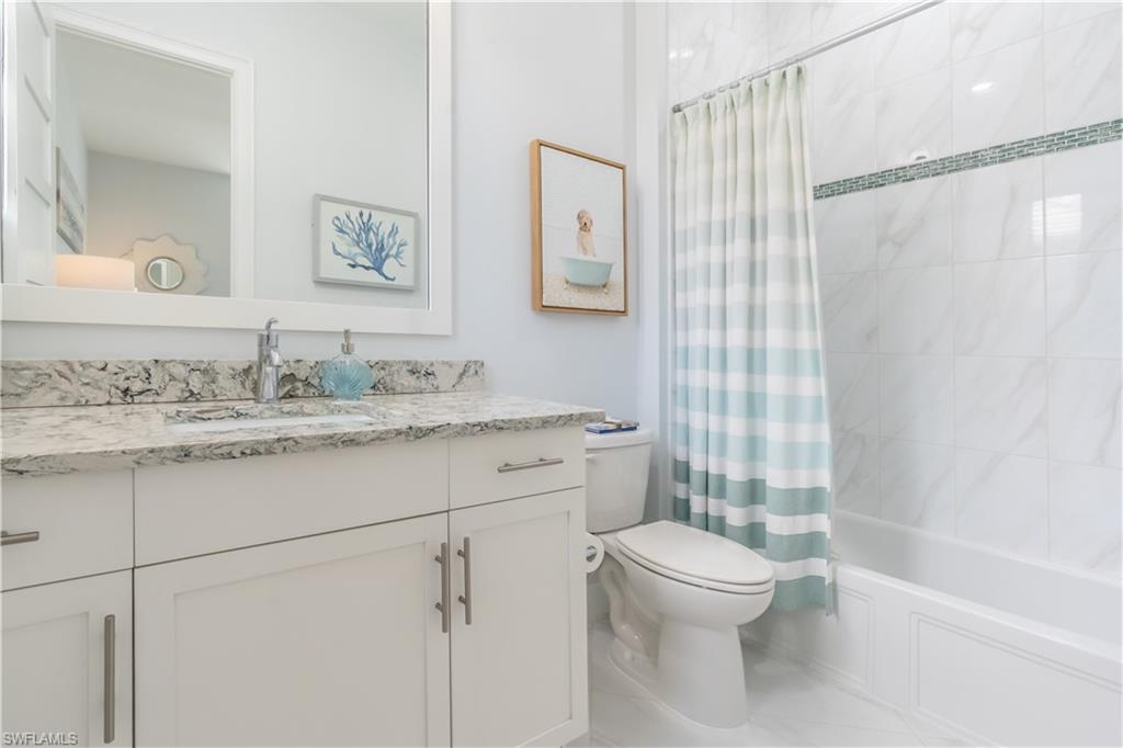 5060 Martinique Drive Naples, FL 34113 - Photo 38 of 49 An adjoining charming bathroom has a tub and shower, beautiful granite top vanity and large mirror.