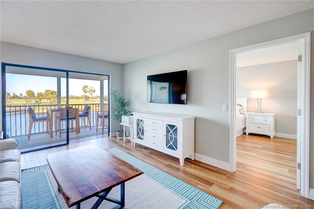 40 Northeast Plantation Road, Unit 203 Jensen Beach, FL 34957 - Photo 26 of 53 a living room with furniture a flat screen tv and a floor to ceiling window
