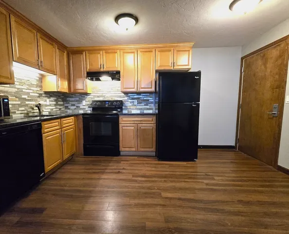 a kitchen with granite countertop wooden cabinets and a refrigerator