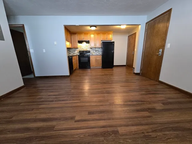 an empty room with wooden floor and stainless steel appliances