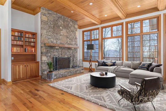 a view of an empty room with wooden floor fireplace and a window
