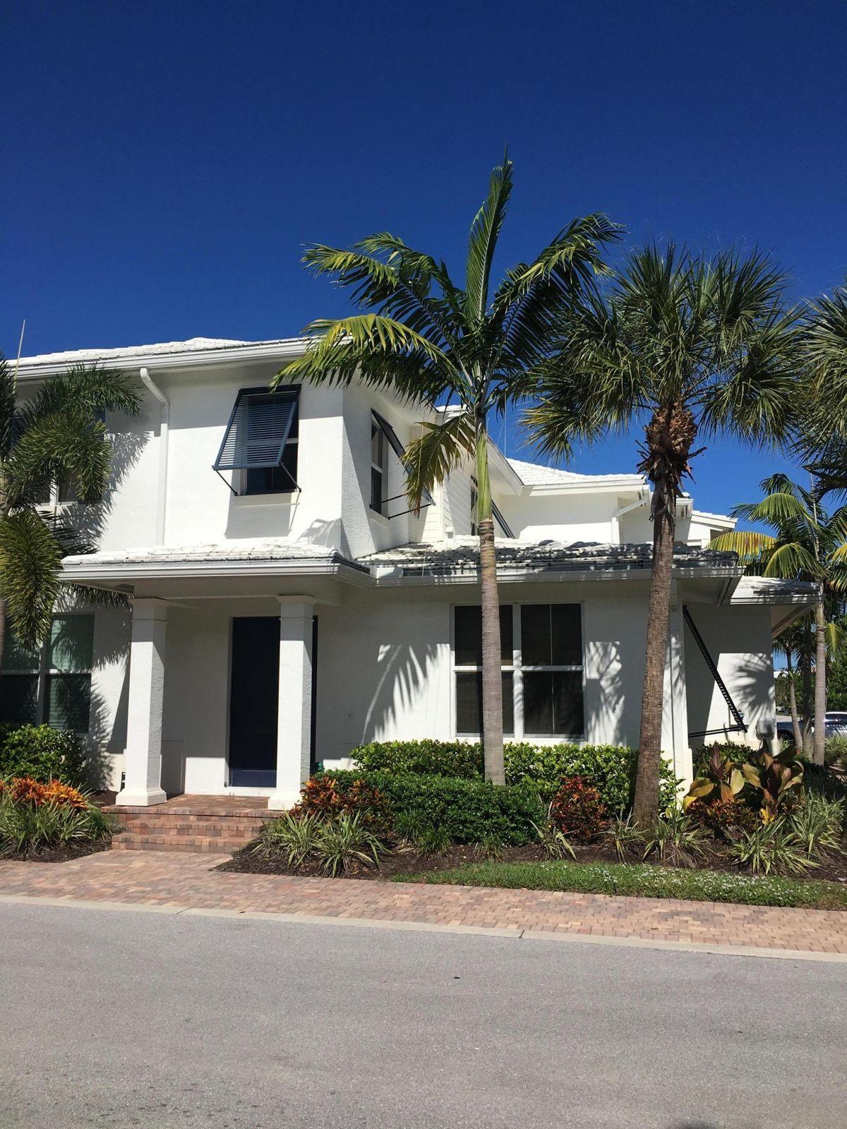 front view of house with potted plants and palm trees