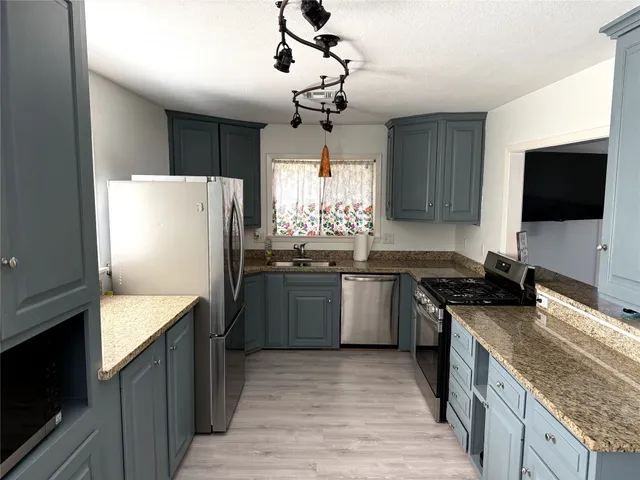 a kitchen with stainless steel appliances granite countertop a sink stove and refrigerator
