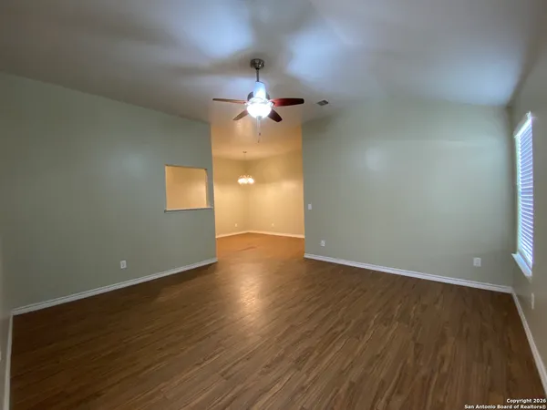 a view of empty room with wooden floor and fan
