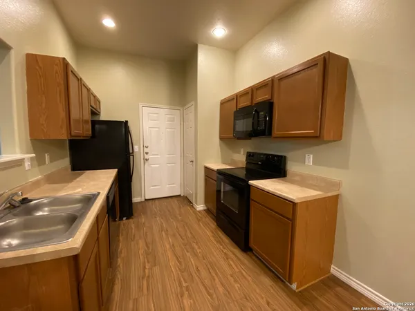 a kitchen with a sink a stove top oven and wooden floor