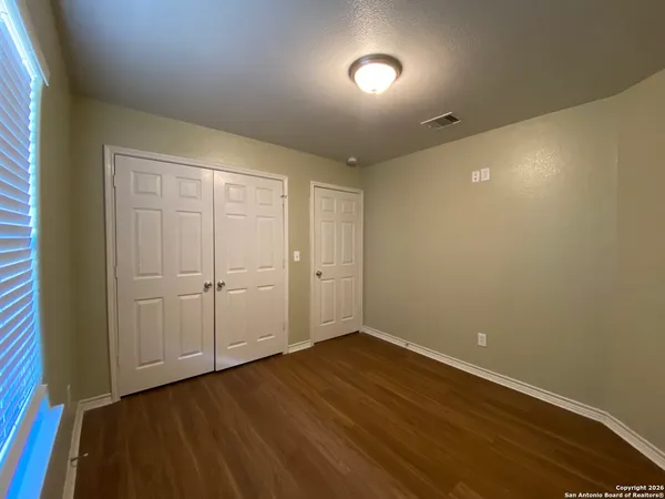 a view of an empty room with wooden floor and closet