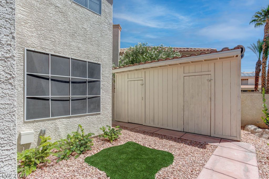 1 Rising Sun Court Henderson, NV 89074 - Photo 37 of 47 A quaint side yard features a practical shed and a small patch of artificial turf.