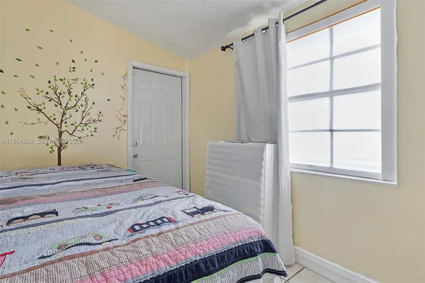 a bedroom with a bed and a window with chair