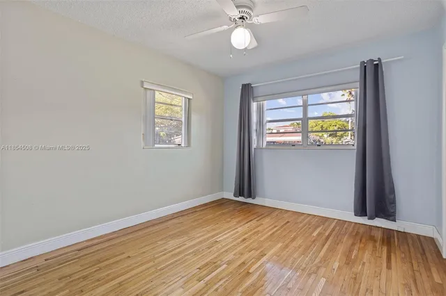 a view of empty room with wooden floor and fan