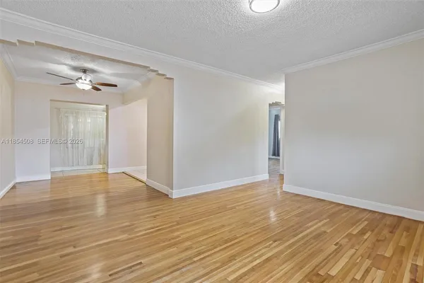 a view of an empty room and chandelier fan
