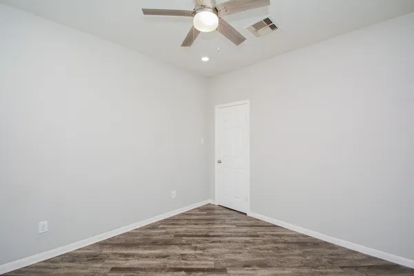 a view of a room with wooden floor and a ceiling fan