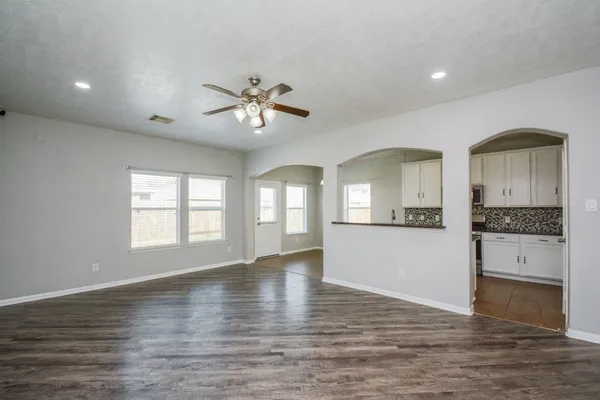 a view of an empty room with window and wooden floor
