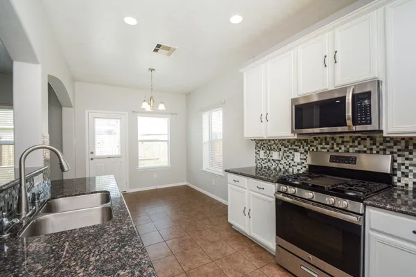 a kitchen with stainless steel appliances granite countertop a stove a sink and a microwave