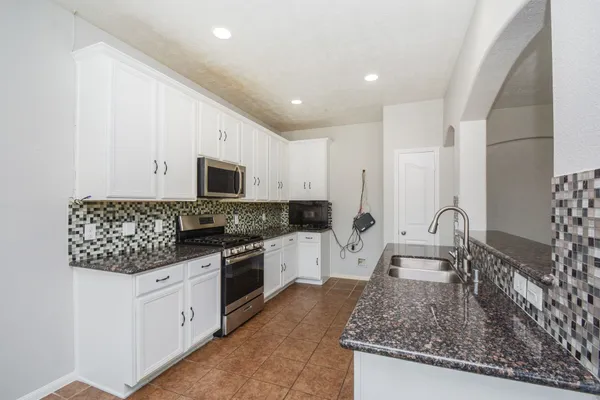 a kitchen with granite countertop a sink stainless steel appliances and white cabinets