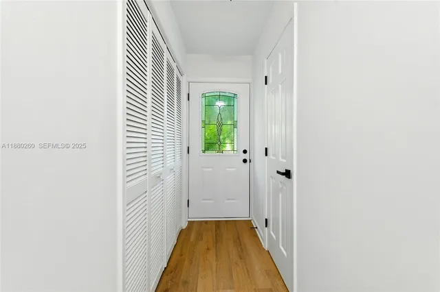 a view of a hallway with wooden floor and a bathroom