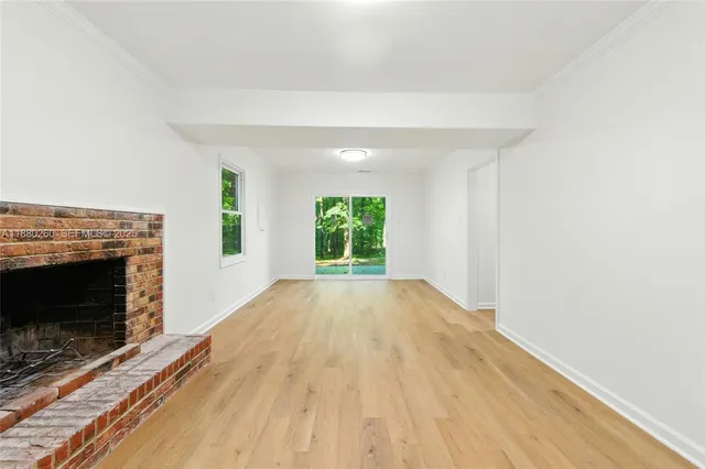 a view of empty room with wooden floor and fireplace