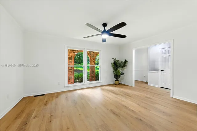 a view of an empty room with a window and wooden floor