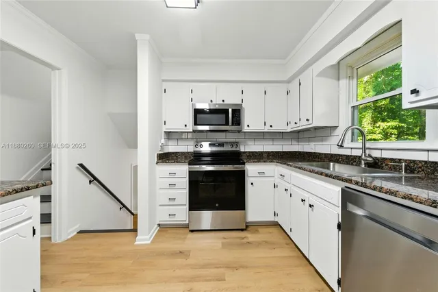 a kitchen with granite countertop a stove top oven cabinetry a sink and a potted plant