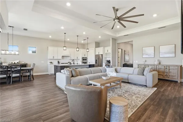 a living room with furniture kitchen view and a wooden floor
