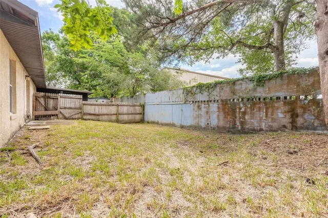 a view of a backyard with large trees and wooden fence