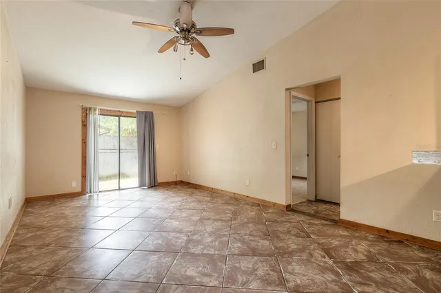 a view of an empty room with window and chandelier fan
