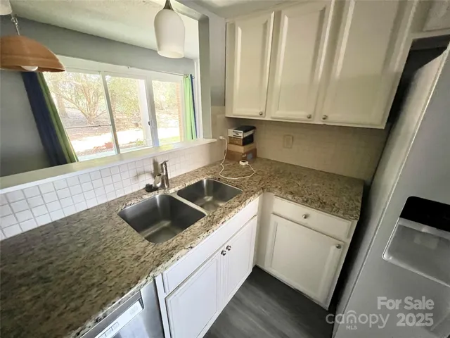 a kitchen with granite countertop a sink stove and cabinets