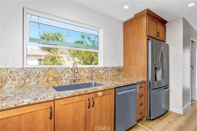 a kitchen with granite countertop a refrigerator and a sink