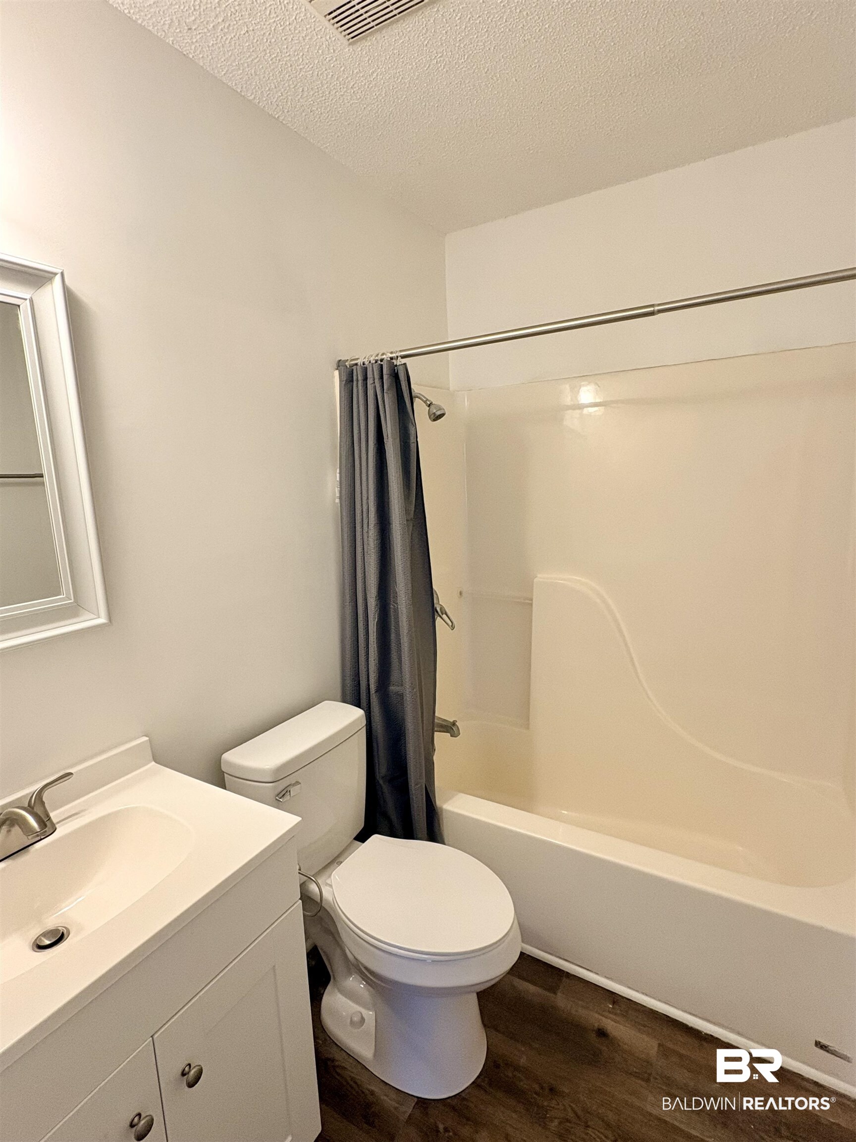 47 Fairview Street Evergreen, AL 36401 - Photo 7 of 15 Full bath featuring a textured ceiling, vanity, dark wood-style floors, and shower / bath combo with shower curtain