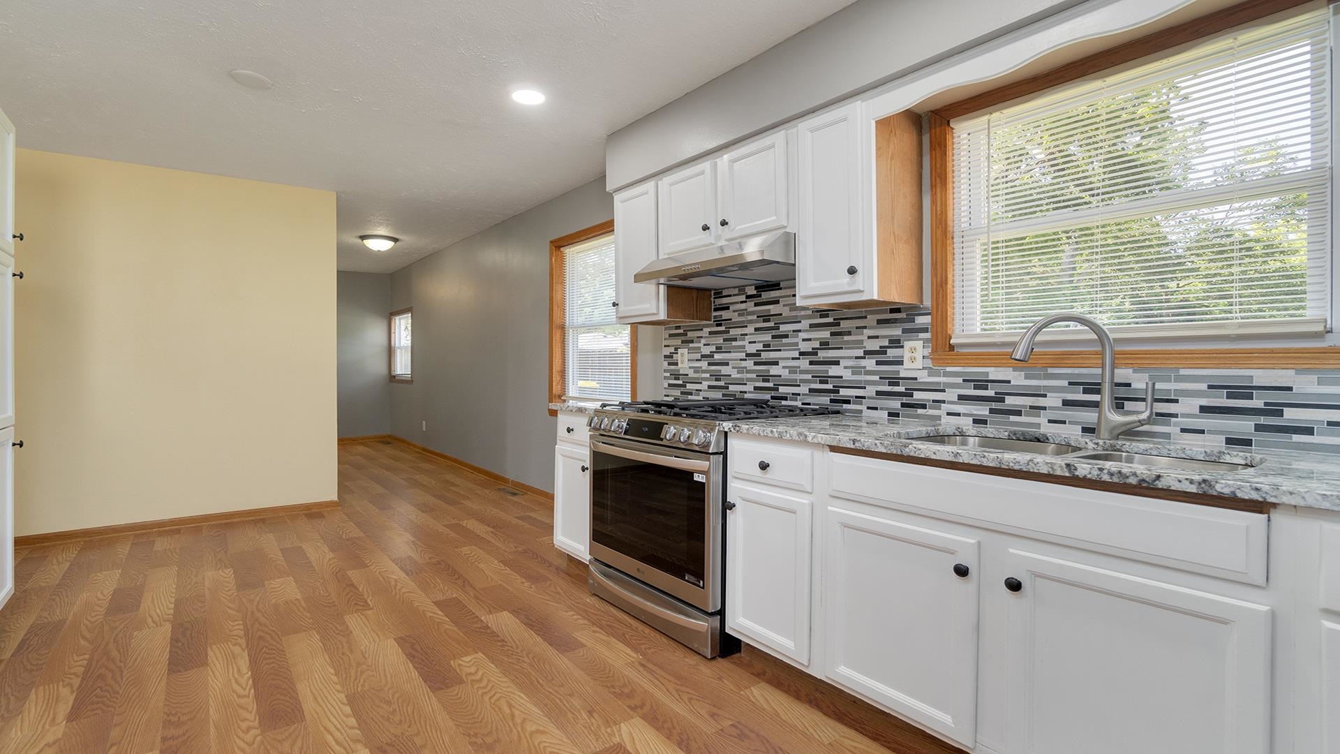 820 East Riverside Boulevard Loves Park, IL 61111 - Photo 11 of 32 a kitchen with stainless steel appliances granite countertop a stove a sink and white cabinets with wooden floor