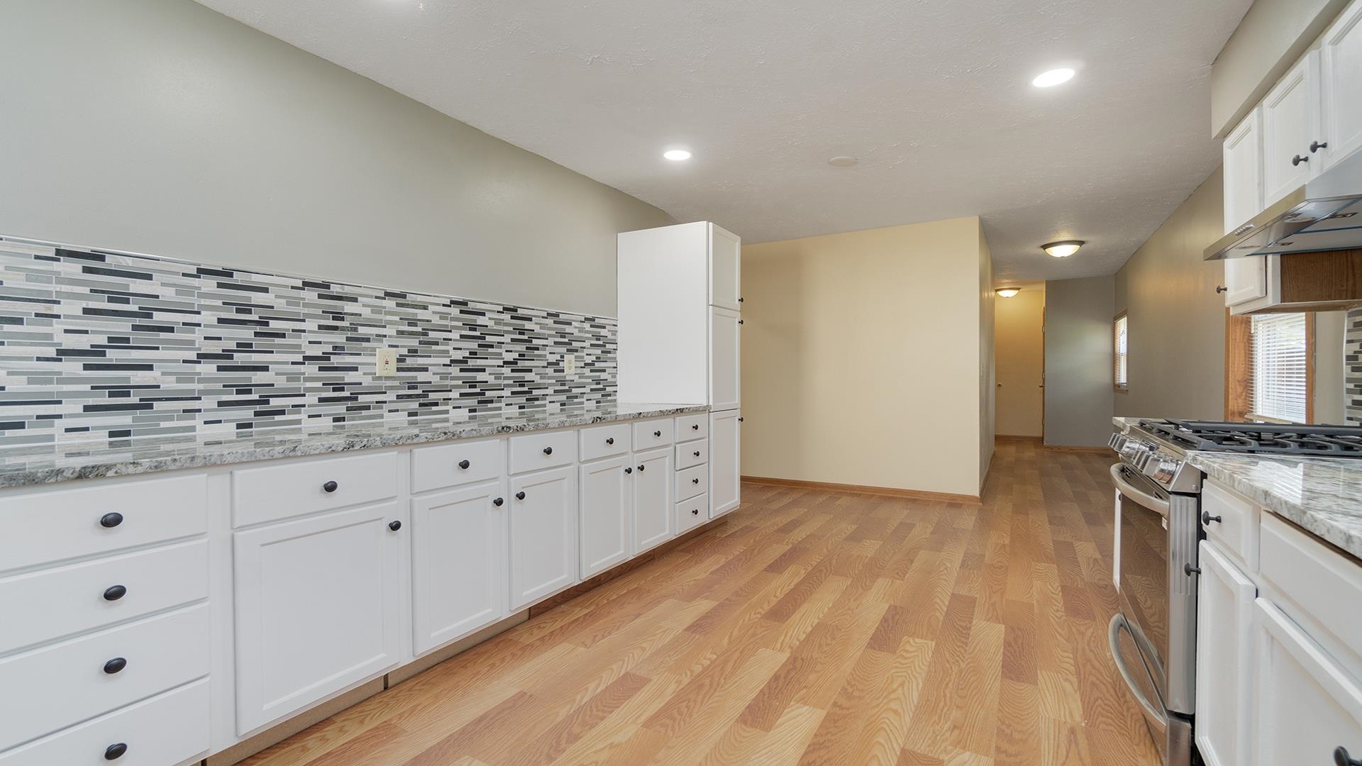 820 East Riverside Boulevard Loves Park, IL 61111 - Photo 9 of 32 a kitchen with stainless steel appliances granite countertop a stove a sink and white cabinets with wooden floor