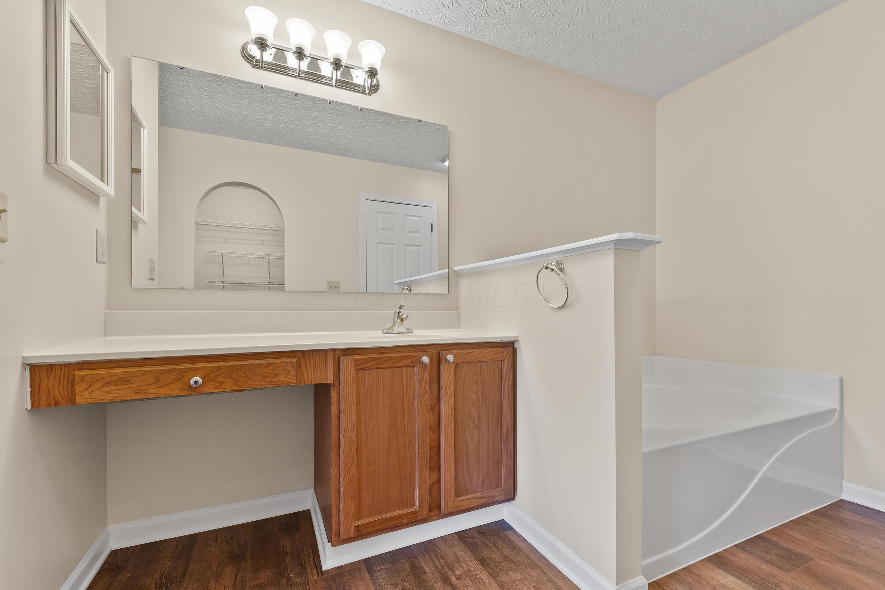 30 Tabilore Loop Delaware, OH 43015 - Photo 33 of 55 • New luxury vinyl plank flooring ~ 2025 • Tan painted walls • Enclosed vanity with single bowl, cultured marble sinktop & vanity area • 4 bulb wall light • Mirrored medicine cabinet • Garden tub • Lighted ceiling exhaust