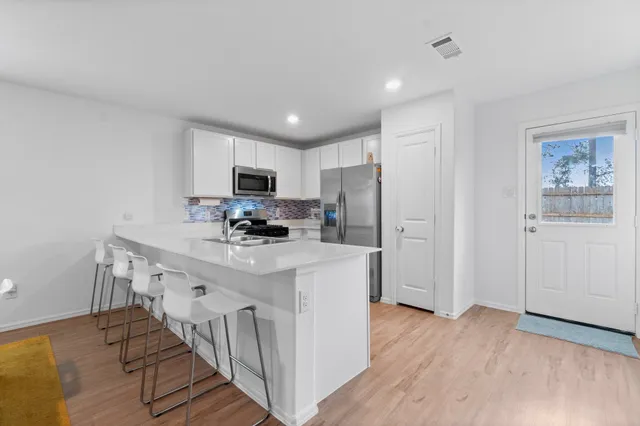 a kitchen with stainless steel appliances granite countertop a stove top oven a sink dishwasher and a refrigerator with wooden floor