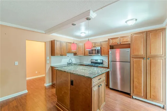a kitchen with stainless steel appliances granite countertop a refrigerator a sink and a stove