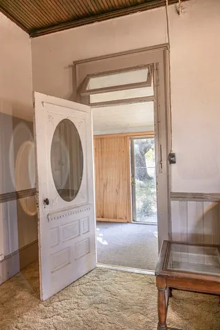 a view of a hallway with wooden floor and a large mirror