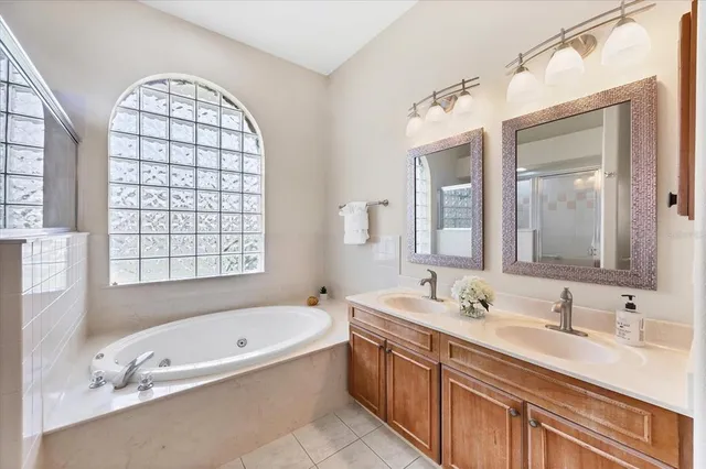 a bathroom with a tub a double vanity sink a mirror a window and a bathtub