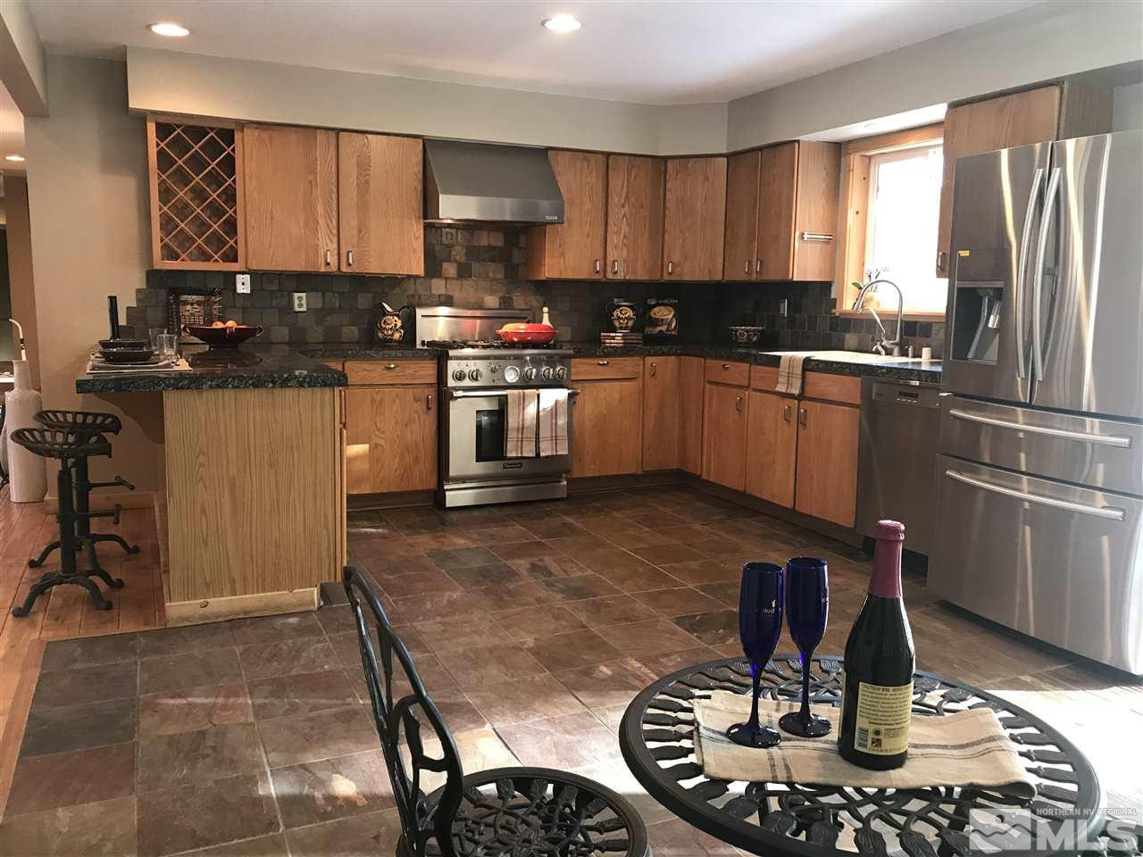 21715 Sazarac Road Reno, NV 89521 - Photo 9 of 25 a kitchen with sink a refrigerator and chairs