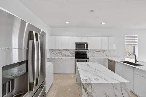 a kitchen with stainless steel appliances granite countertop a refrigerator sink and stove