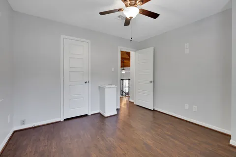 an empty room with wooden floor and ceiling fan