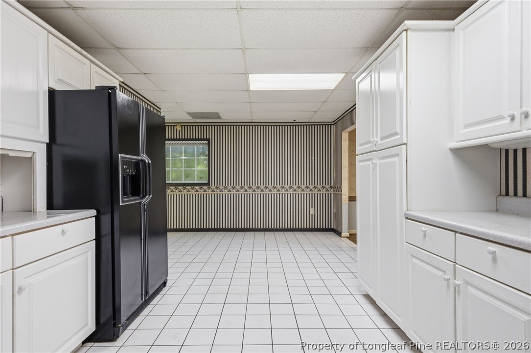 478 Rattlesnake Trail Aberdeen, NC 28315 - Photo 24 of 44 a view of a refrigerator in kitchen and an empty room with wooden floor