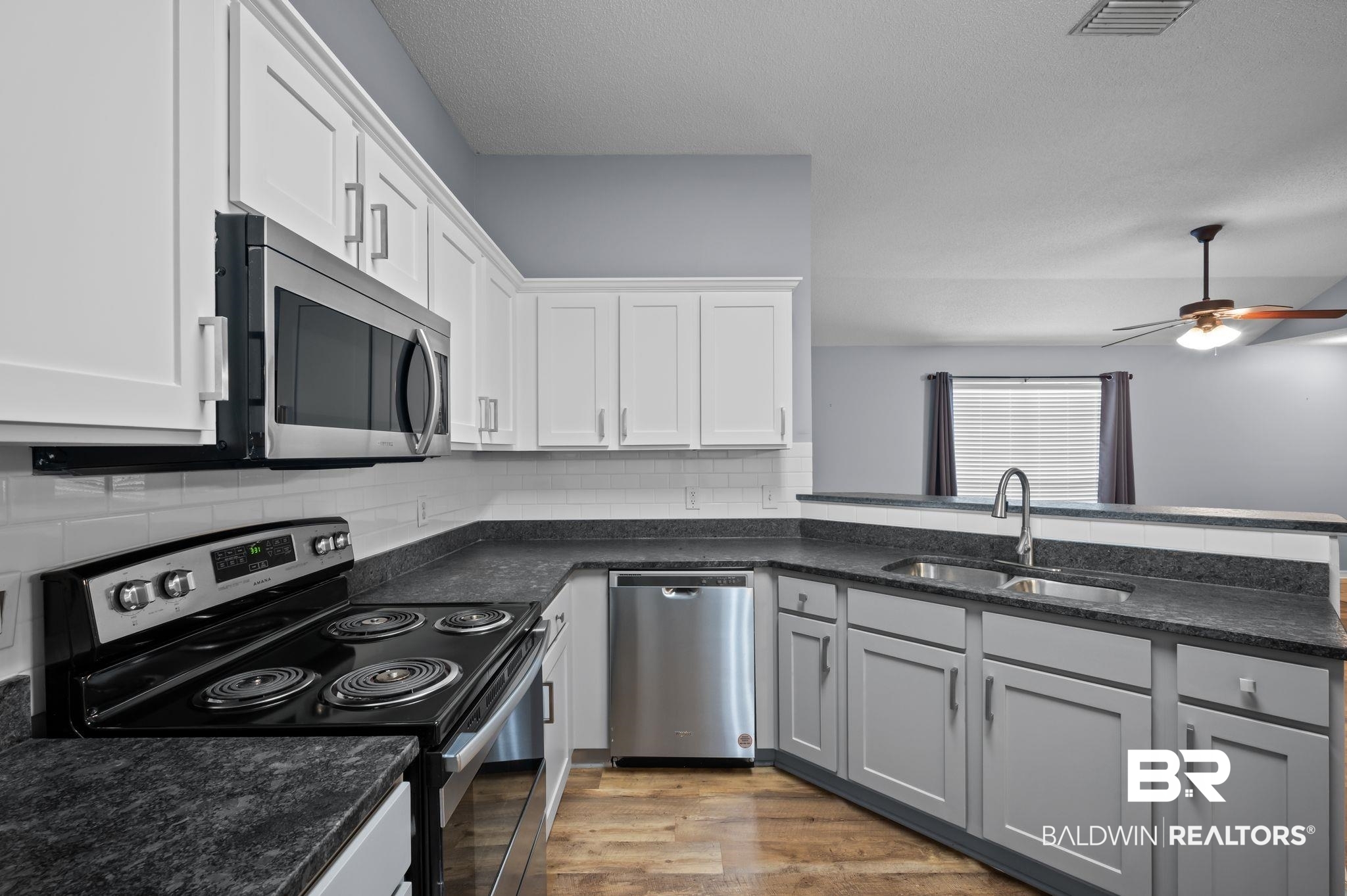 8901 Fall Court Mobile, AL 36695 - Photo 3 of 23 Kitchen with stainless steel appliances, wood finished floors, ceiling fan, white cabinets, and backsplash