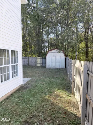 a backyard of a house with a small barn and wooden fence