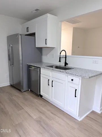 a kitchen with granite countertop white cabinets and stainless steel appliances