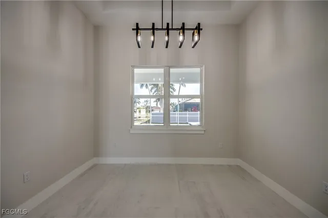 a view of empty room with window and chandelier fan