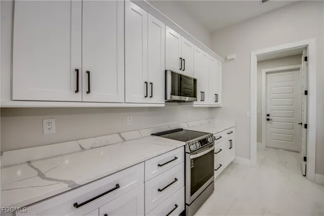 a kitchen with stainless steel appliances granite countertop white cabinets and a stove