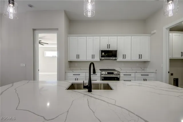 a kitchen with stainless steel appliances a stove a sink and white cabinets