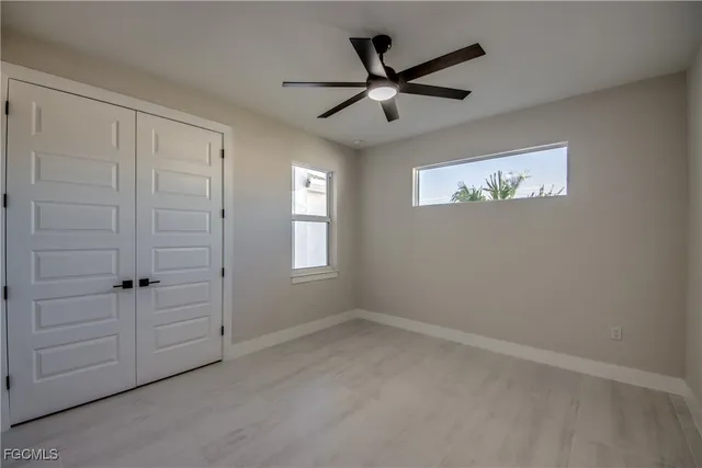 an empty room with windows and fan