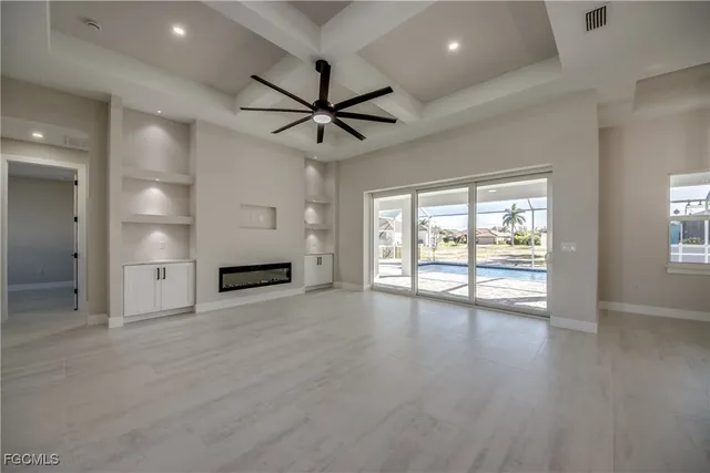 an empty room with wooden floor ceiling fan and windows